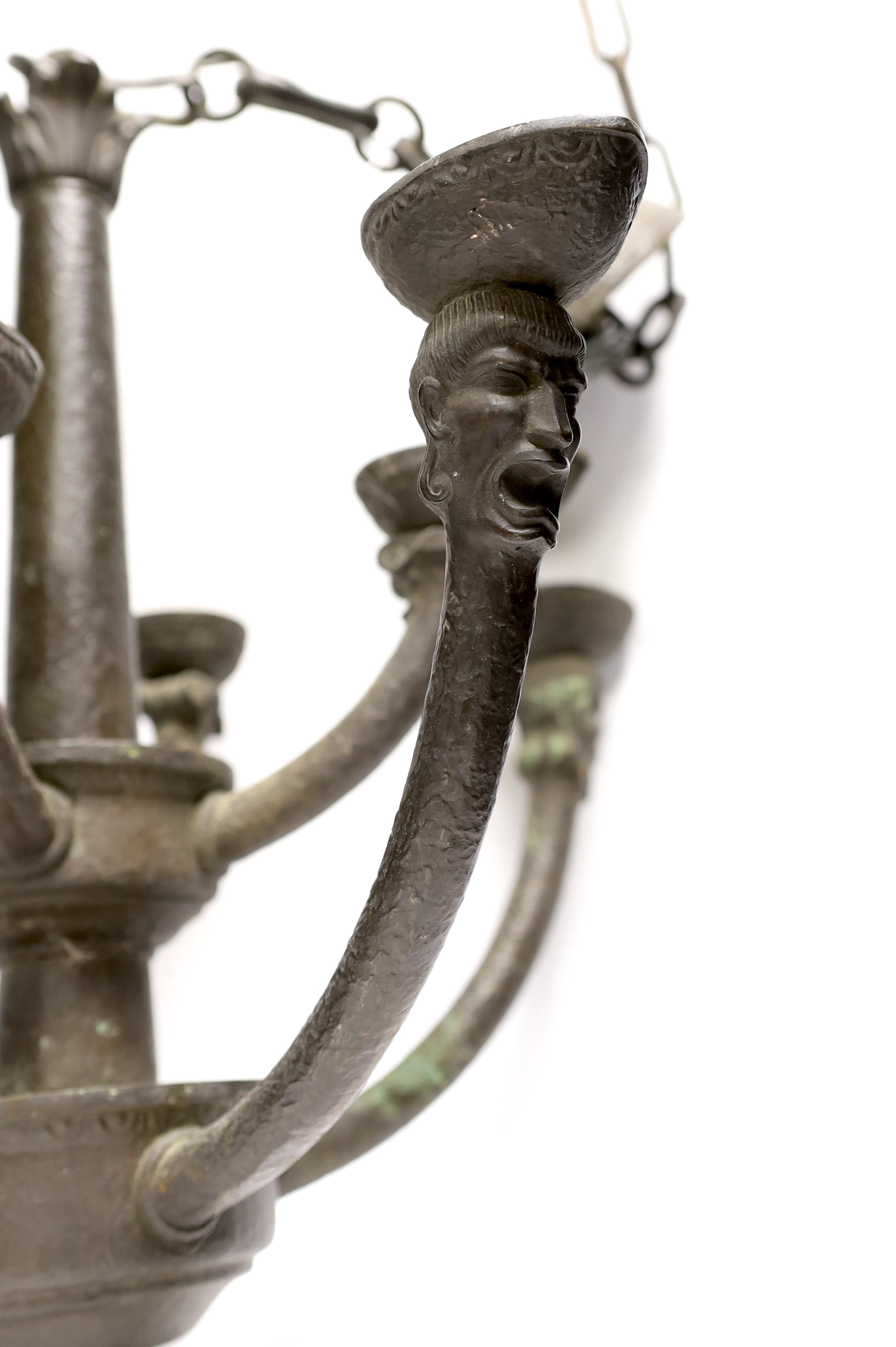 A bronze hanging ceiling light, with two tiers and eight face mask branches and large central chain, approx 47cm high not including chain